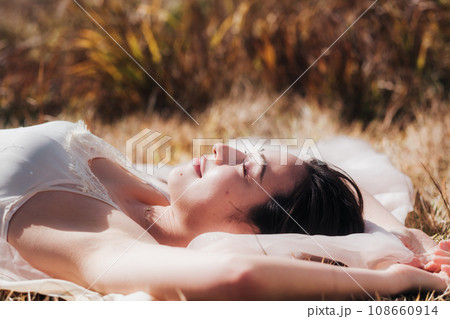 夕方に草原に寝転ぶ女性　ビューティーイメージ 108660914