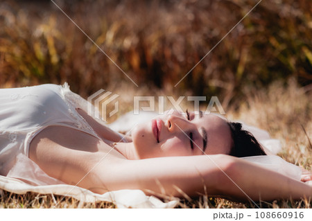 夕方に草原に寝転ぶ女性 ビューティーイメージ 夕方に草原に寝転ぶ女性 ビューティーイメージ 108660916