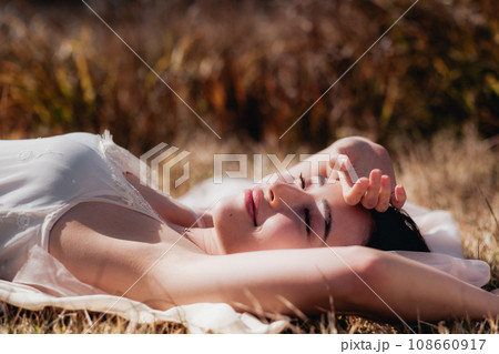 夕方に草原に寝転ぶ女性　ビューティーイメージ 108660917