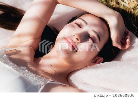 夕方に草原に寝転ぶ女性　ビューティーイメージ 108660936