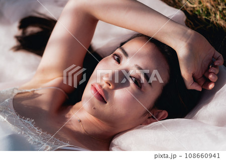 夕方に草原に寝転ぶ女性　ビューティーイメージ 108660941