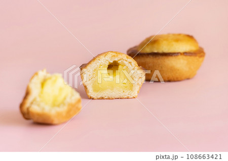 Pasticciotto leccese pastry filled with egg custard cream on a light pink, close up Pasticciotto leccese pastry filled with egg custard cream on a light pink, close up 108663421