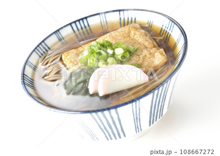 油揚げ、かまぼこ、ワカメ、葱が乗った熱々のきつね蕎麦を白背景で撮影 108667272