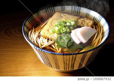 油揚げ、かまぼこ、ワカメ、葱が乗った熱々のきつね蕎麦 108667432