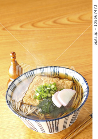 油揚げ、かまぼこ、ワカメ、葱が乗った熱々きつね蕎麦と瓢箪型の唐辛子入れ 油揚げ、かまぼこ、ワカメ、葱が乗った熱々きつね蕎麦と瓢箪型の唐辛子入れ 108667473