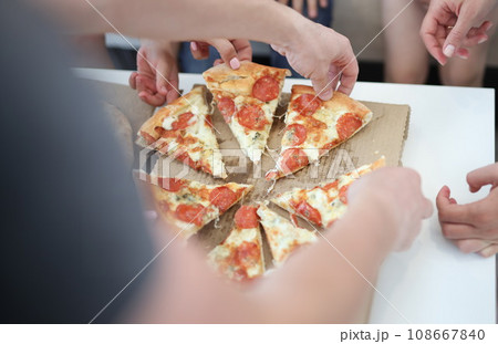 Group of people taking slices of pizza closeup Group of people taking slices of pizza closeup 108667840
