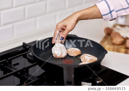 female hands preparing homemade meat cutlets in white kitchen female hands preparing homemade meat cutlets in white kitchen 108669515