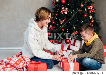 mother and son sit by the tree with gifts New Year Christmas mother and son sit by the tree with gifts New Year Christmas 108669781