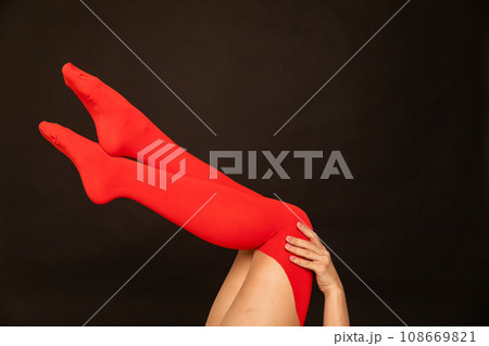 women's slender legs in red stockings on a black background 108669821
