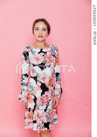 a beautiful woman in a floral dress poses on a pink background a beautiful woman in a floral dress poses on a pink background 108669827