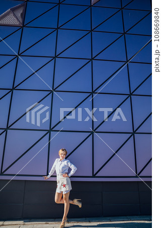 fashionable woman near the big glass wall of the building 108669840