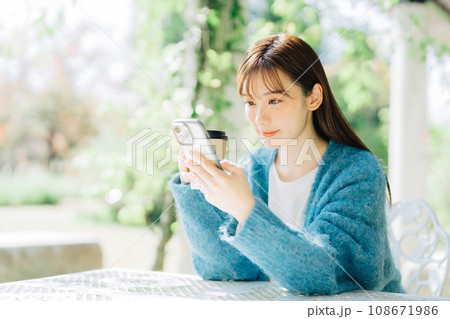 テラスでスマホを見る女性 108671986