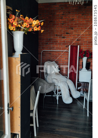 a large soft toy in a chair in a room with flowers a large soft toy in a chair in a room with flowers 108673545