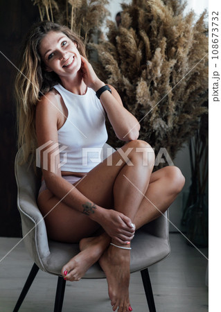 a woman sits in a chair near a dry flower a woman sits in a chair near a dry flower 108673732