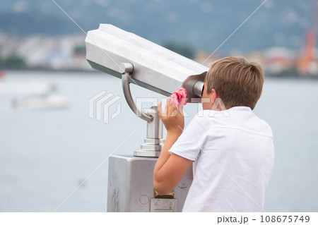 The boy looks at the observation deck in a tourist handheld telescope. 108675749