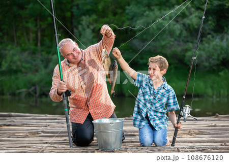 Grandfather and grandson are fishermen with fishing rods and caught fish. Grandfather and grandson are fishermen with fishing rods and caught fish. 108676120
