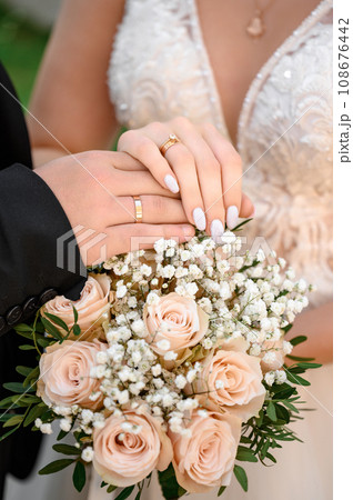 Bouquet for the bride in the hands of the grooms close-up. 108676442