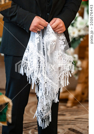 A man holds in his hands a white shawl to cover a woman's head with lace. A man holds in his hands a white shawl to cover a woman's head with lace. 108676443