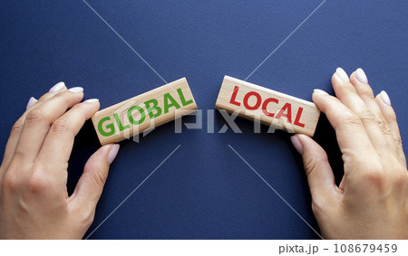 Global and Local symbol. Concept word Global and Local on wooden blocks. Businessman hand. Beautiful deep blue background. Business and Global and Local concept. Copy space Global and Local symbol. Concept word Global and Local on wooden blocks. Businessman hand. Beautiful deep blue background. Business and Global and Local concept. Copy space 108679459