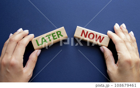 Now vs Later symbol. Concept word Now vs Later on wooden blocks. Businessman hand. Beautiful deep blue background. Business and Now vs Later concept. Copy space 108679461