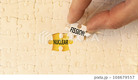 Nuclear fission symbol. Concept words Nuclear fission on beautiful white paper puzzles. Beautiful yellow paper background. Businessman hand. Business science nuclear fission concept. Copy space. 108679557