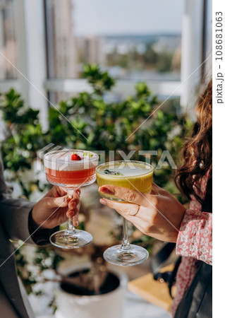 Close up of two female friends clinking and toasting with glass with cocktails in restaurant or bar Close up of two female friends clinking and toasting with glass with cocktails in restaurant or bar 108681063