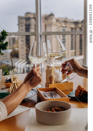 Close up of hands toasting wine glasses at dinner in restaurant. Drinks and celebration concept Close up of hands toasting wine glasses at dinner in restaurant. Drinks and celebration concept 108681109