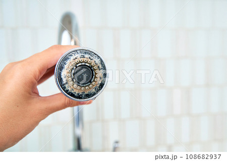 A woman is holding a chrome faucet covered with lime scale. A woman is holding a chrome faucet covered with lime scale. 108682937