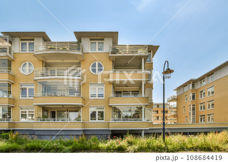 an apartment building with balks on the balconys and balks on the second floor in the photo is clear blue sky 108684419
