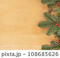 Christmas flat lay of green fir branches, red berries and brown cones at the right. 108685626