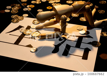 散らばった小銭の中で生活に苦しみ、項垂れている様子の人形 108687662