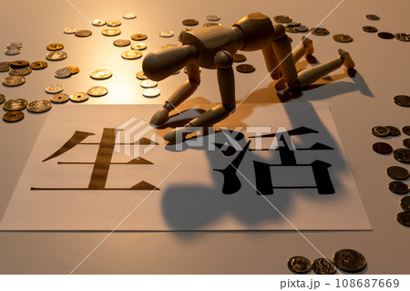 散らばった小銭の中で生活に苦しみ、項垂れている様子の人形 108687669