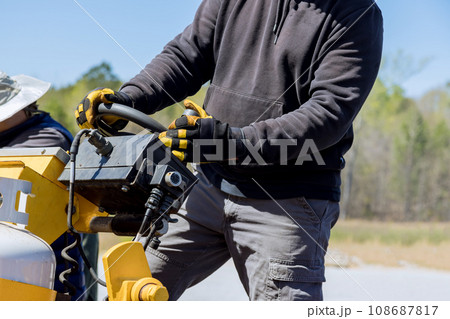 During highway construction, pavement machine lays fresh bitumen asphalt over gravel base 108687817