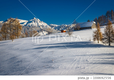 Idyllic winter landscape with snowy wooden hut and high mountains 108692556