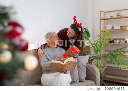 Family winter holiday and concept happy mother and daughter decorate christmas tree and give a gift at home Family winter holiday and concept happy mother and daughter decorate christmas tree and give a gift at home 108694038