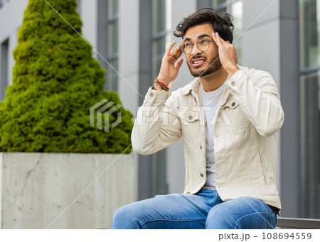Displeased sick Indian man rubbing temples to cure headache problem, suffering from migraine, stress 108694559