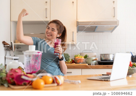 Beauty healthy asian woman making fruit smoothie with blender. woman drinking glass of fruit smoothie in kitchen. Diet concept. healthy drink Beauty healthy asian woman making fruit smoothie with blender. woman drinking glass of fruit smoothie in kitchen. Diet concept. healthy drink 108694662
