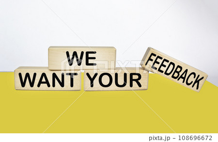 We need your feedback text on wooden block and yellow and white background 108696672
