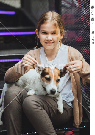 Cute teenage blonde girl with dog on the steps.  108697696