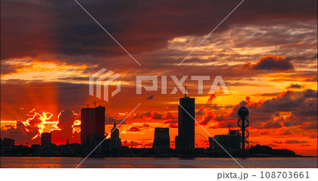 Batumi, Adjara, Georgia. View From Sea Beach To Cityscape With Modern Urban Architecture, Skyscrapers And Tower. Embankment At Sunset Sunrise. Bright Evening Sky In Yellow, Orange And Red Colors Batumi, Adjara, Georgia. View From Sea Beach To Cityscape With Modern Urban Architecture, Skyscrapers And Tower. Embankment At Sunset Sunrise. Bright Evening Sky In Yellow, Orange And Red Colors 108703661