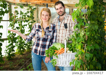 Male and female workers holding harvest Male and female workers holding harvest 108704417