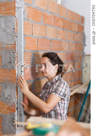 Woman measuring wall with level 108704792