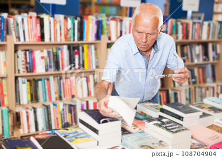 Older male visitor choosing for necessary book in bookstore Older male visitor choosing for necessary book in bookstore 108704904