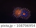夜空に咲く大輪の花、オレンジ色と青色の打ち上げ花火 108706954