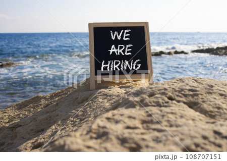 We are Hiring symbol. Concept words We are Hiring on black chalk blackboard blocks. Beautiful sea background. Business and We are Hiring concept. Copy space. We are Hiring symbol. Concept words We are Hiring on black chalk blackboard blocks. Beautiful sea background. Business and We are Hiring concept. Copy space. 108707151