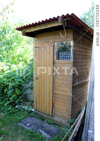 A rustic summer toilet is a light homemade wooden building in the garden 108710288