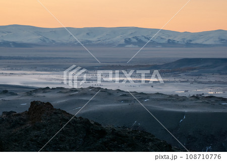 Misty morning mountain valley. Sun rises behind the mountain. .Valley with the river in the distance is covered with fog. Hiking on a mountain trail. Misty morning mountain valley. Sun rises behind the mountain. .Valley with the river in the distance is covered with fog. Hiking on a mountain trail. 108710776