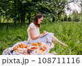 Beautiful woman on picnic. She smiles, eats strawberries and enjoys summer. 108711116
