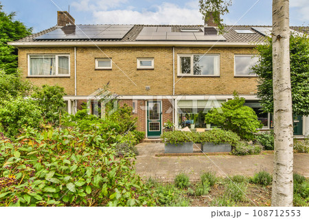 an outside view of a house with solar panels on the roof and trees in the fore - image taken from above an outside view of a house with solar panels on the roof and trees in the fore - image taken from above 108712553