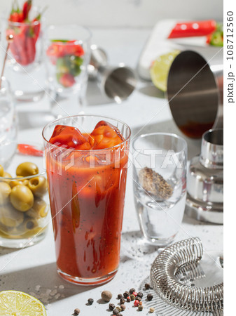 Cocktail bloody mary with pepper,lime,bar shaker and strainer on light board. Top view. Cocktail bloody mary with pepper,lime,bar shaker and strainer on light board. Top view. 108712560
